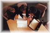 Business Professionals Gathered Around a Table Perusing Print Documents